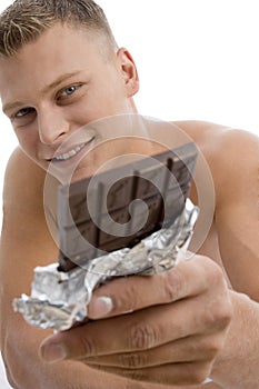 Smiling muscular guy showing chocolate