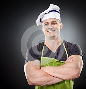Smiling muscular man cook with arms folded