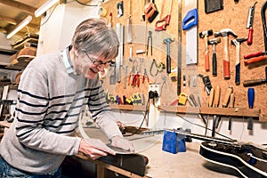 Smiling musical instrument maker working on a guitar