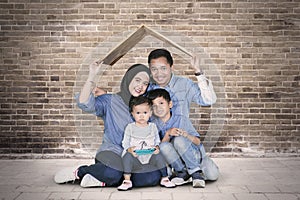 Smiling Muslim family sits under a roof symbol