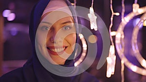 Smiling Muslim Woman Standing Next to the Hanging Moon and Star Decorations