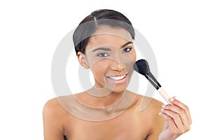 Smiling natural model using blusher brush