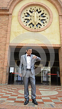 Smiling newlywed groom posing in front of old stairs in suit