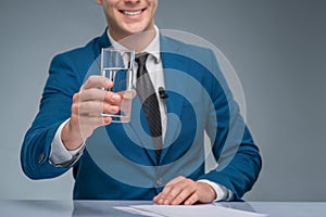 Smiling newsman holding a glass of water