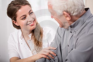Smiling nurse assisting senior man photo