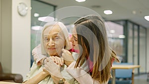 Smiling nurse embracing a senior woman in geriatrics