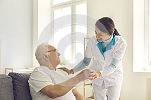 Smiling nurse giving glass of water to senior man in nursing home or assisted living facility