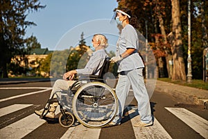 Smiling nurse helping senior man to walk around the city street