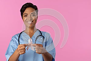 Smiling nurse holding breast cancer awareness pink ribbon with both hands