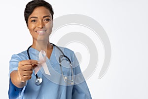 Smiling nurse holding breast cancer awareness pink ribbon between her fingers