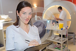 Smiling nurse holding clipboard scan mri