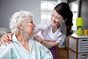 Smiling nurse and old woman patient at wheelchair