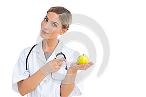 Smiling nurse pointing to green apple on her hand