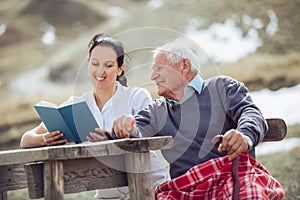 Smiling nurse reading book to senior man