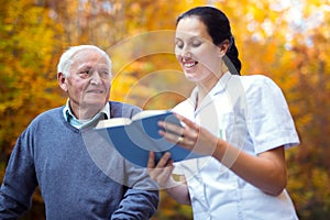 Smiling nurse reading book to senior man