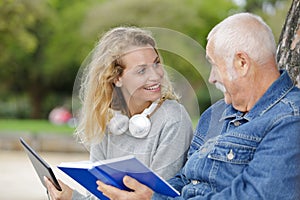 Smiling nurse reading book to senior man outdoor