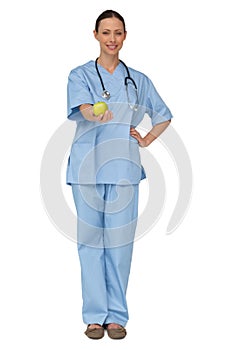 Smiling nurse in scrubs holding green apple