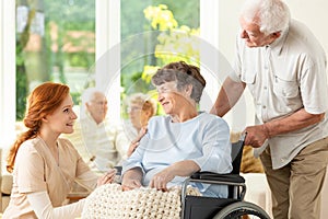 Smiling nurse and senior man supporting paralyzed elderly woman