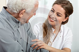 Smiling nurse sitting at table with senior patient