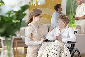 Smiling nurse taking care of happy paralyzed senior woman in the