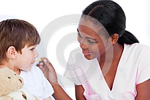 Smiling nurse taking little boy's temperature