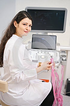 Smiling nurse working on ultrasound scanner in the clinic