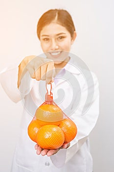 Smiling nutritionist holding orange