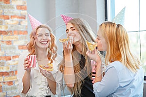 Smiling office lady, at lunchtime and eating pizza. Festive atmosphere.