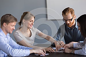 Smiling office team assembling puzzle together at meeting, teamb