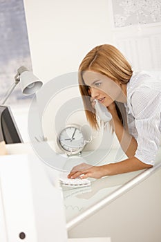 Smiling office worker on call using computer