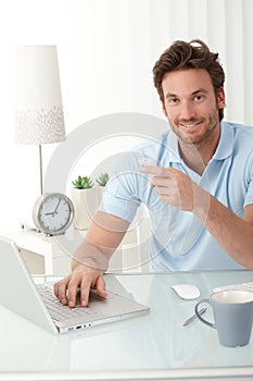 Smiling office worker at desk with phone handheld