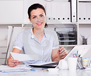 Smiling office worker sitting with documents