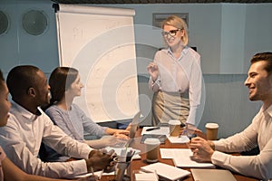 Smiling old coach giving presentation on flipchart training young employees