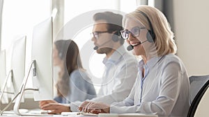 Smiling old female call center agent in headset consulting client photo