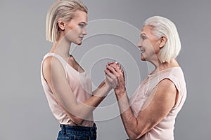Smiling old lady with grey hair gently touching hands