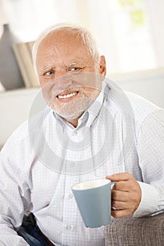 Smiling old man having coffee