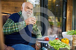 Smiling old man is preparing a vegetable salad