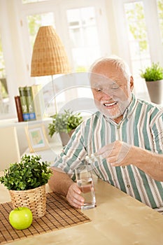 Smiling old man taking medication