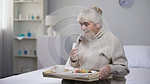 Smiling old woman eating dinner in nursing home, social security for aged people