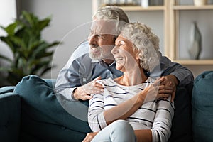 Smiling older couple dreaming together, looking out window