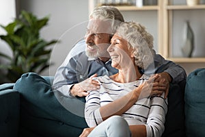 Smiling older couple dreaming together, looking out window photo