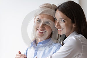 Smiling older mom and grownup daughter hugging