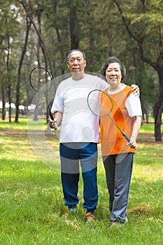 Smiling older sibling and sister holding badminton racket