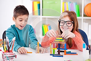 smiling older sister playing with little brother with wooden blocks