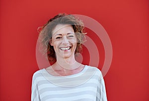 Smiling older woman with curly hair against red wall