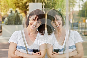 Smiling older woman leaning against reflection in building outside