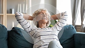 Smiling older woman leaning back, relaxing on cozy couch