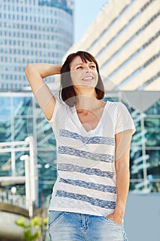 Smiling older woman standing in city with hand in hair