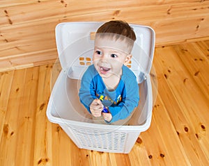 Smiling one year old boy getting out from garbage can