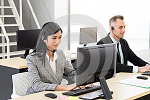 Smiling operator asian woman customer service agent working on computer in call center